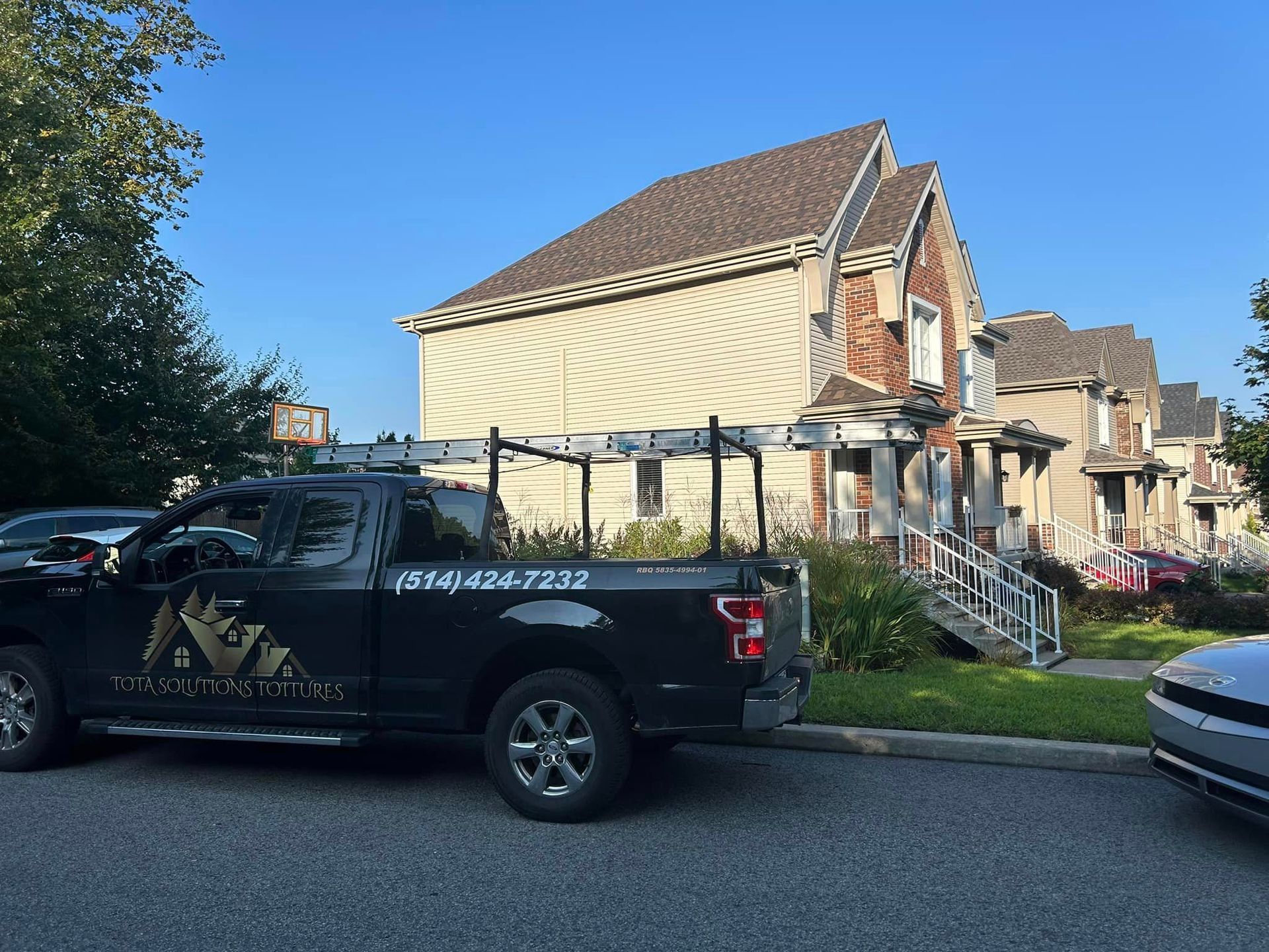 Un camion noir est garé devant une maison.