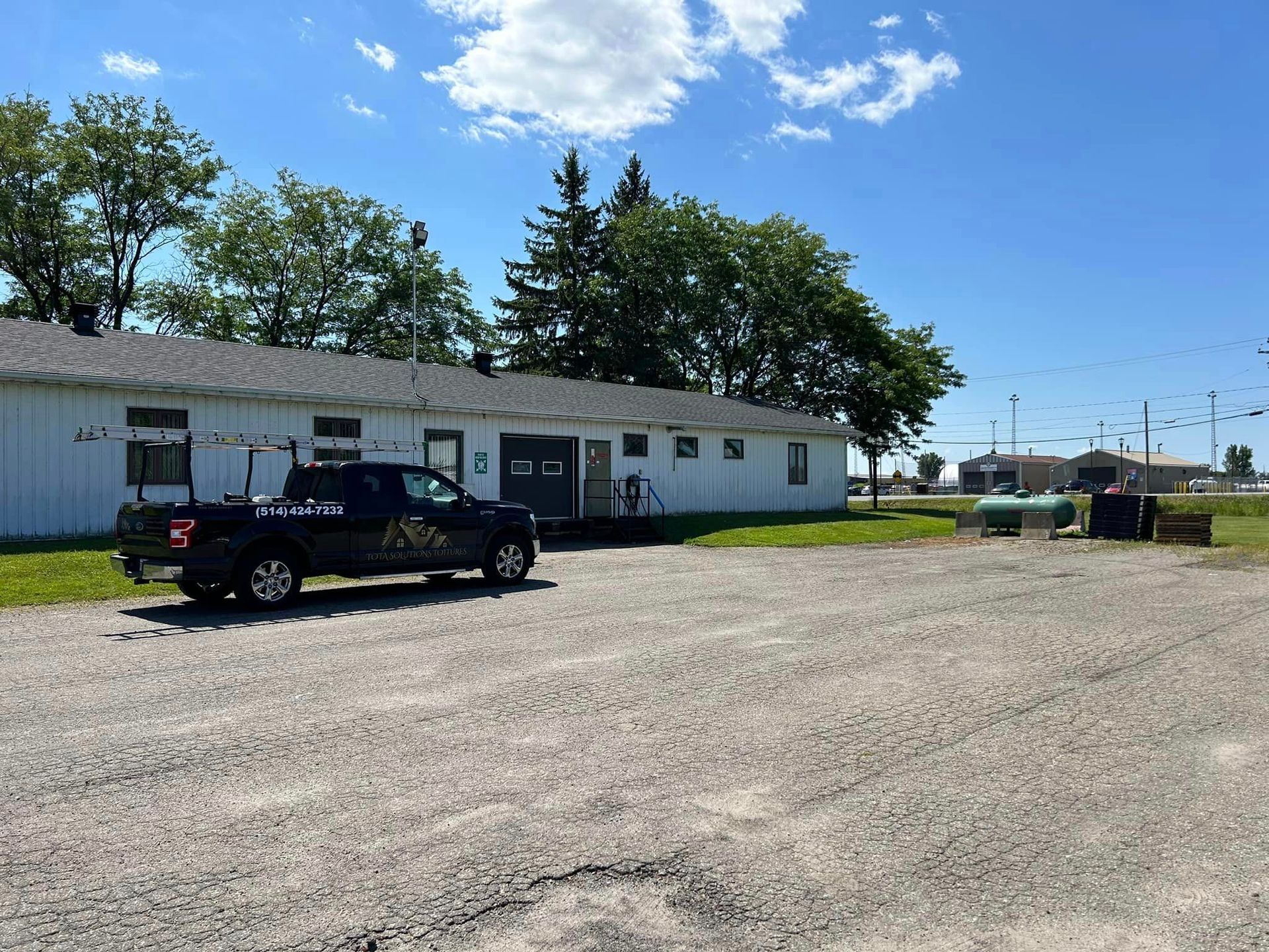 Un camion noir est garé devant un bâtiment blanc.