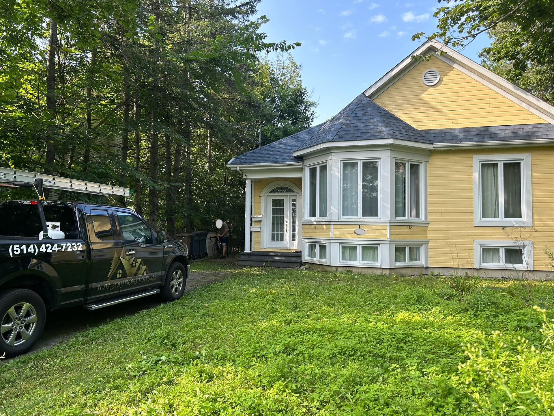 Un camion est garé devant une maison jaune.