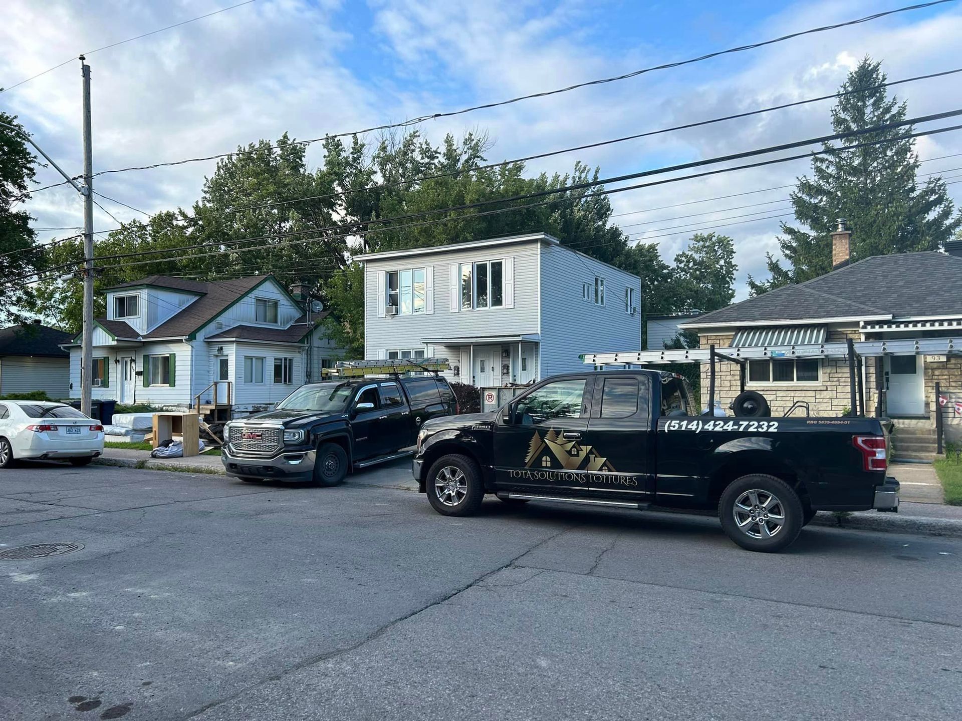 Un camion noir est garé sur le bord de la route devant une maison.