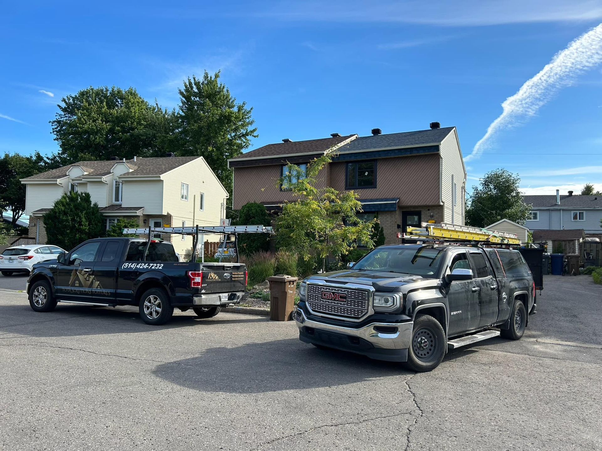 Deux camions sont garés dans une allée devant une maison.