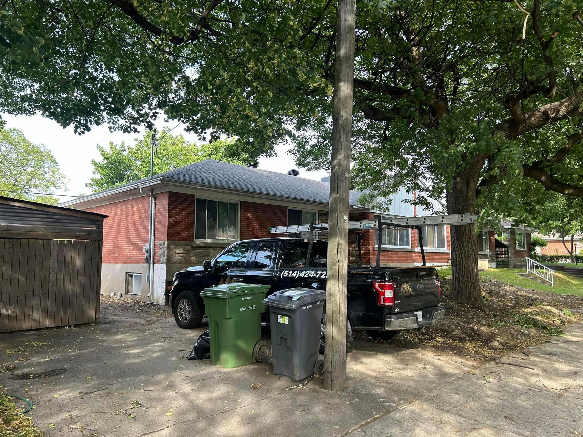 Un camion noir est garé devant une maison en briques.