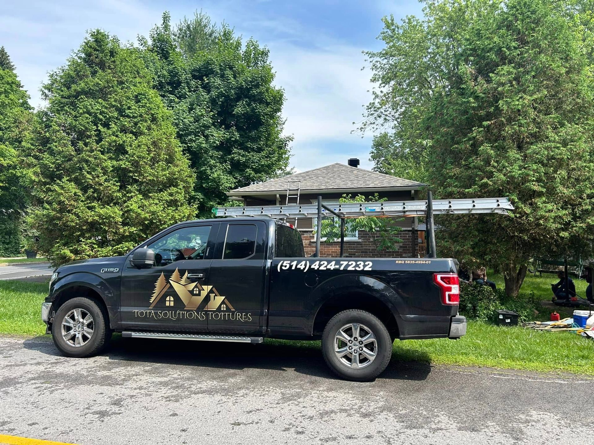 Un camion noir est garé devant une maison.
