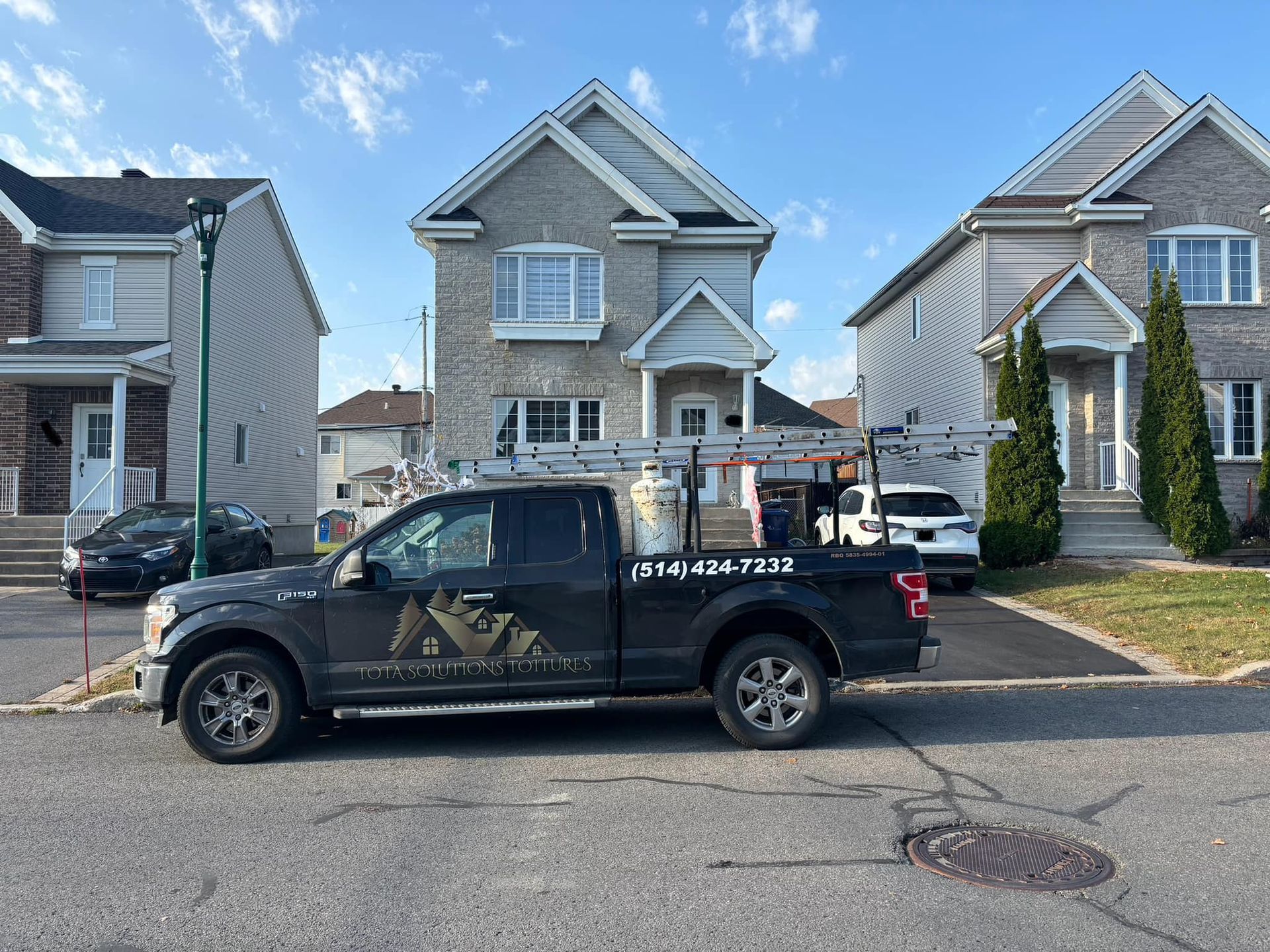 Un camion noir est garé devant une maison.