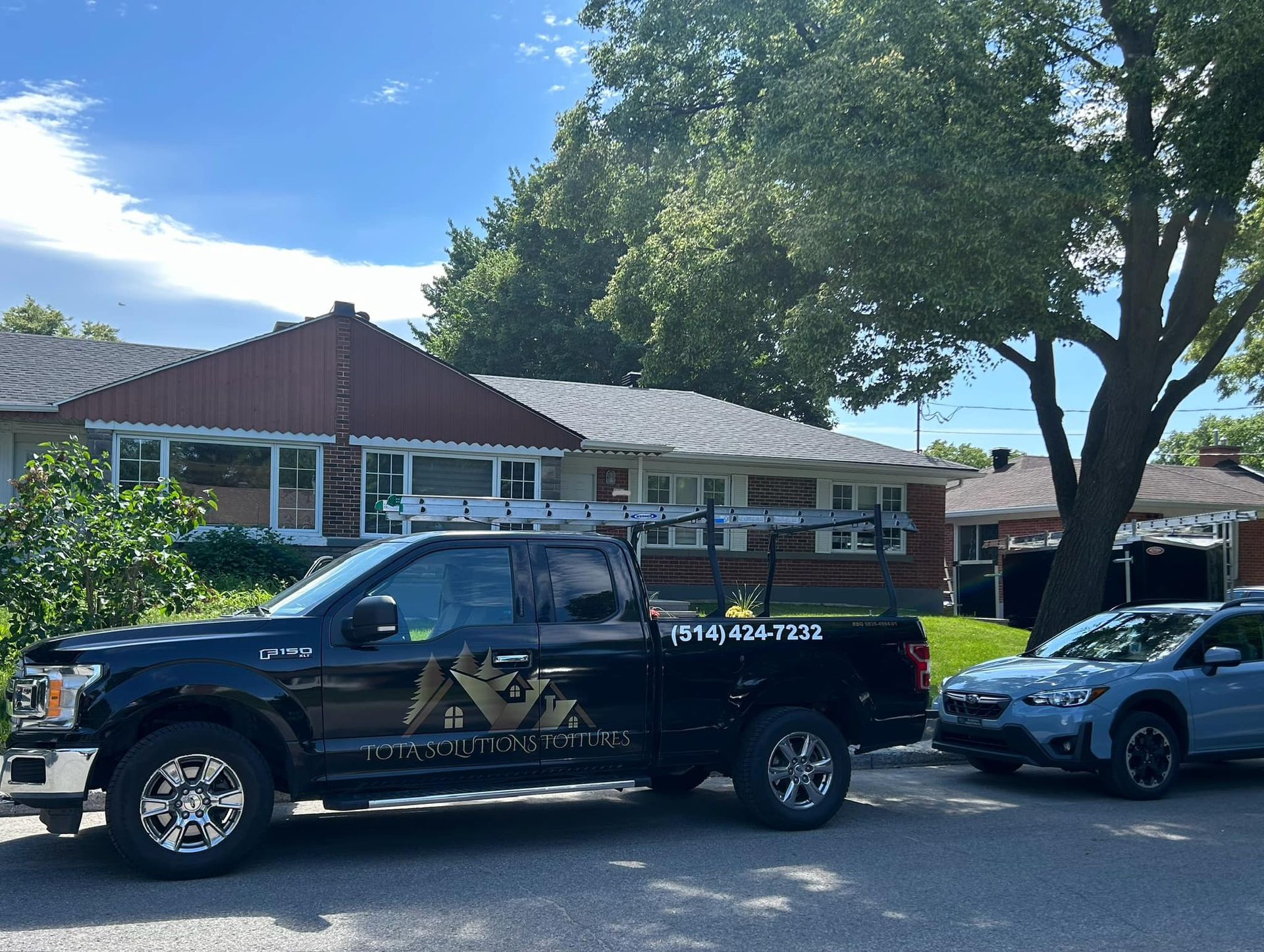 Un camion noir est garé devant une maison.