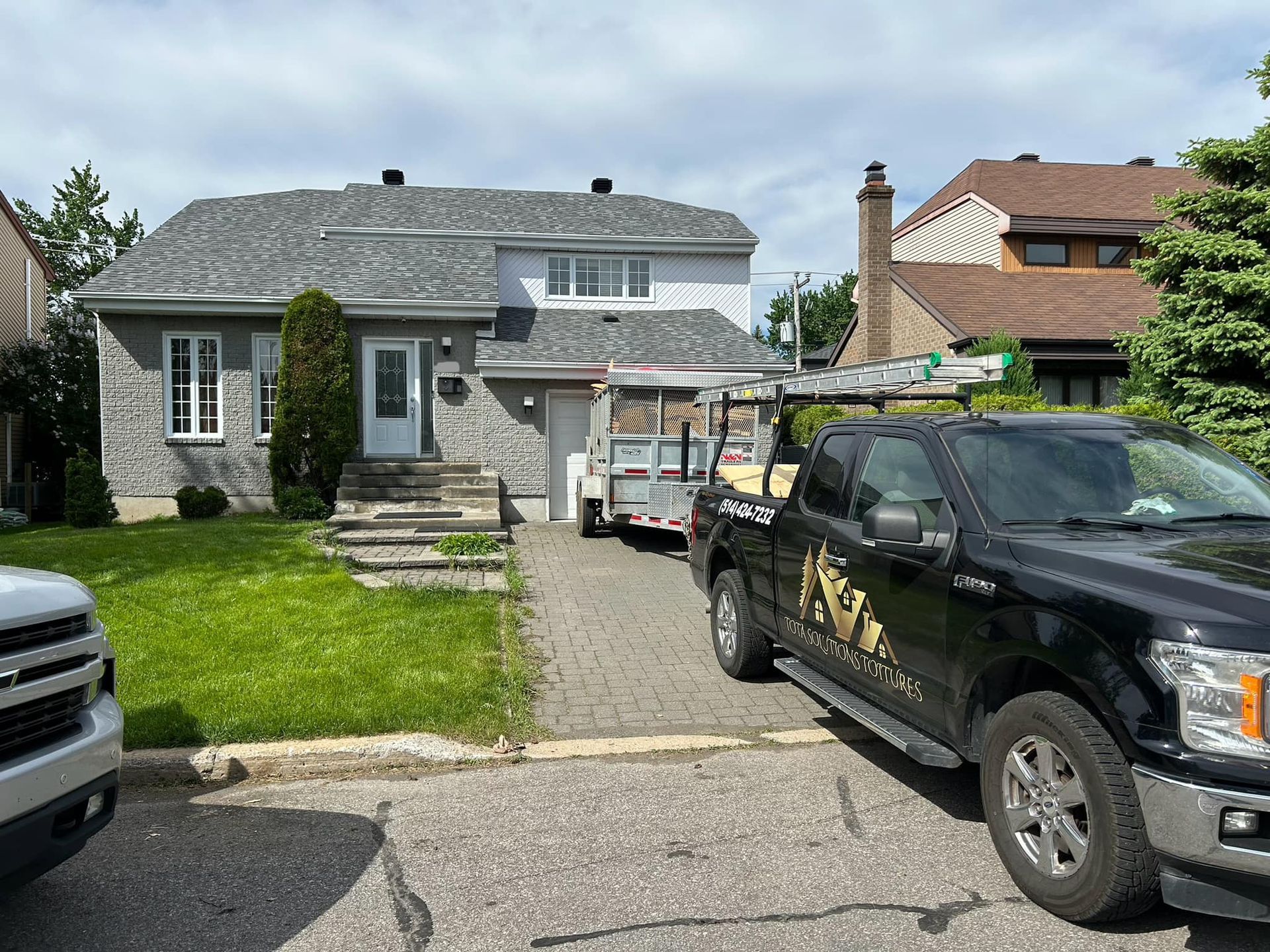Un camion noir est garé devant une maison.