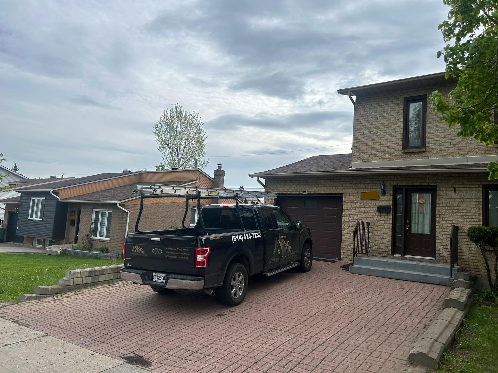 Un camion noir est garé devant une maison en briques.