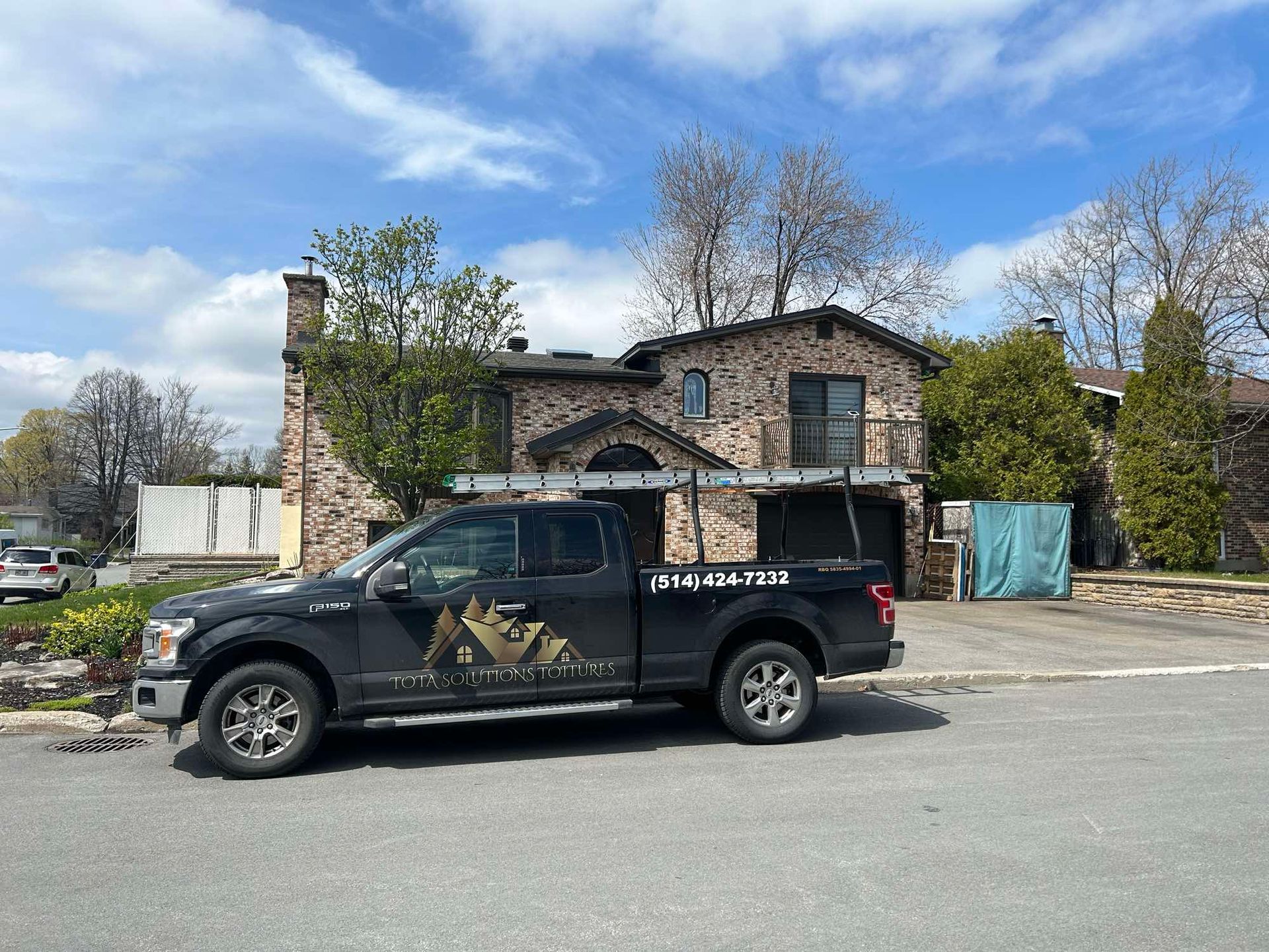 Un camion noir est garé devant une grande maison.