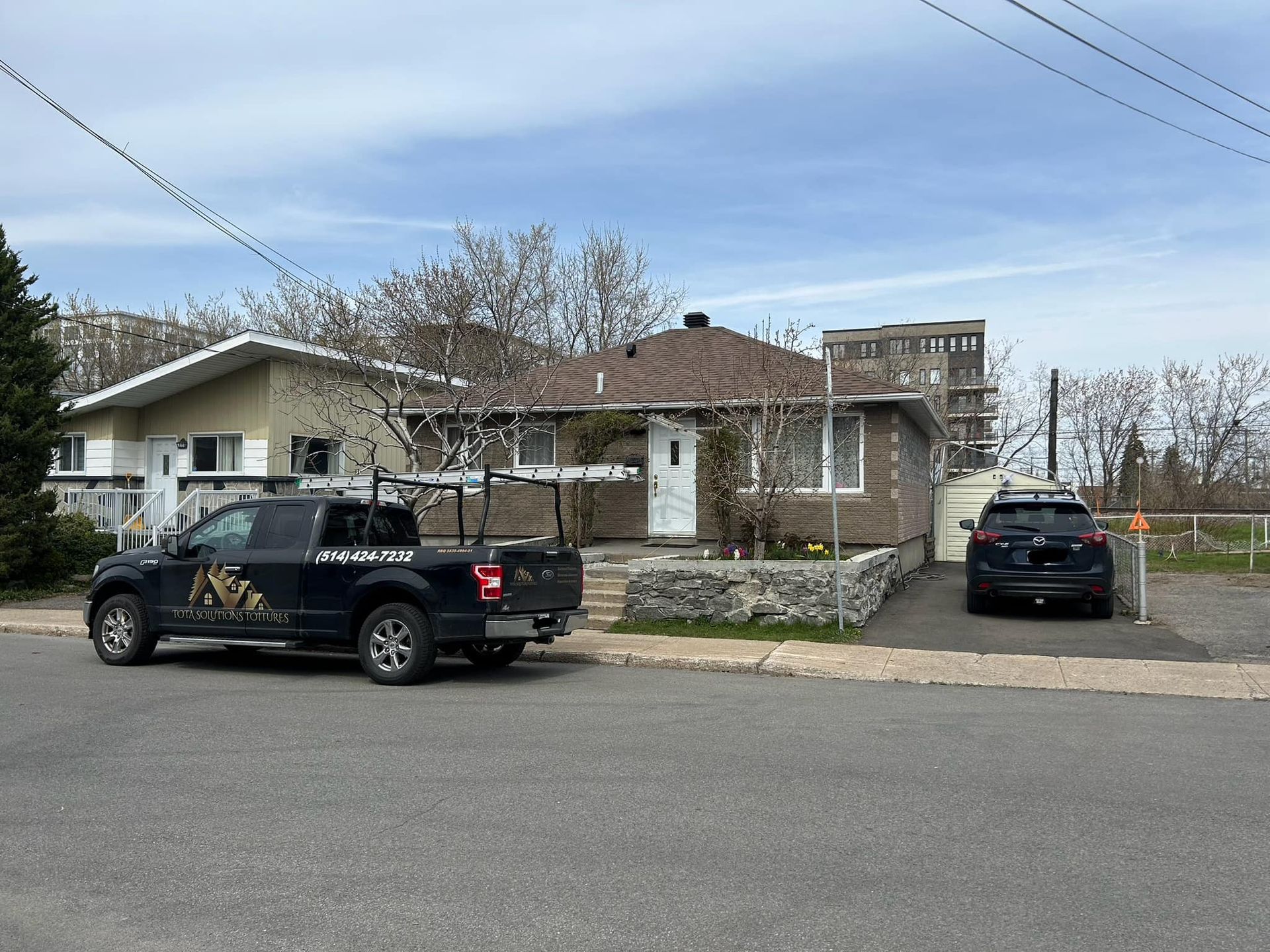 Un camion noir est garé devant une maison.
