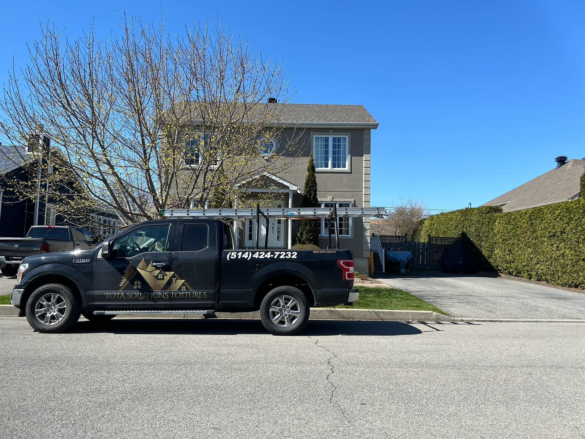 Un camion noir est garé devant une maison.