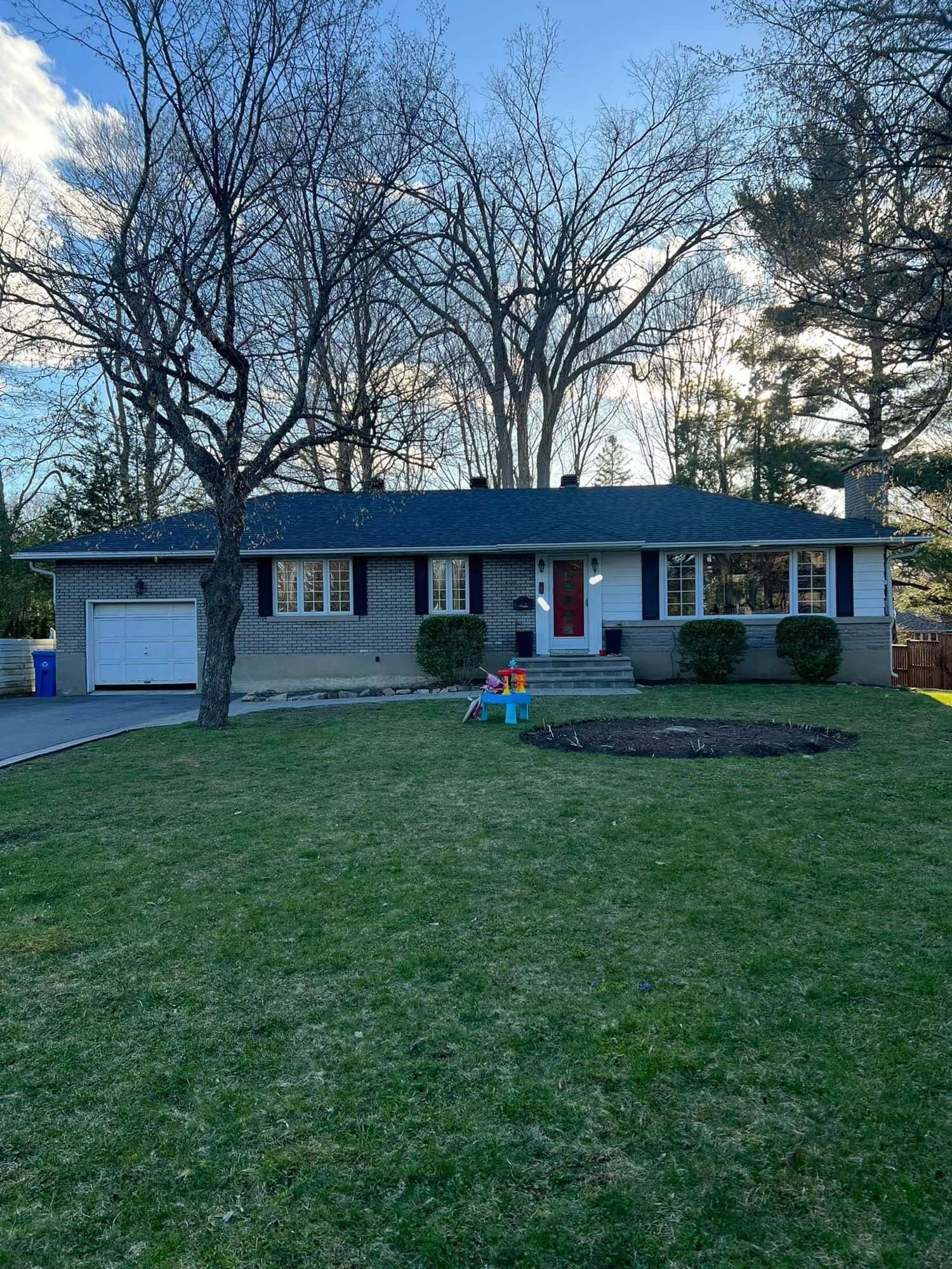 Une maison avec un toit bleu et une grande pelouse devant.
