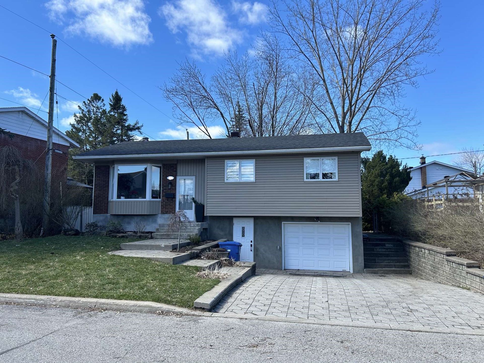 Une petite maison avec un garage et des escaliers devant.