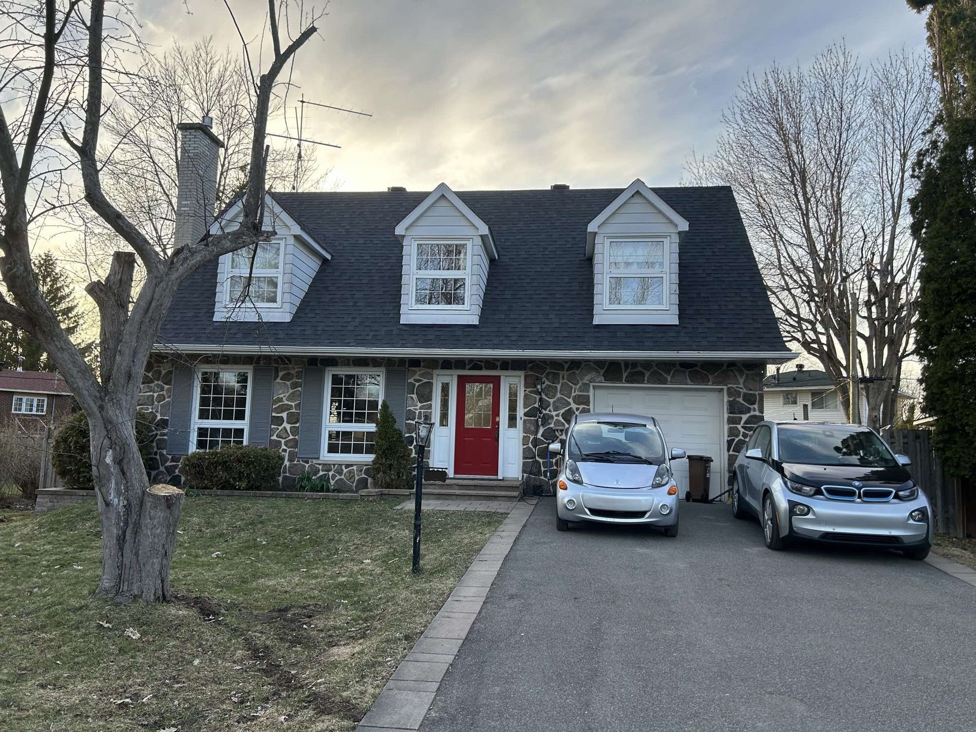 Deux voitures sont garées devant une maison avec une porte rouge