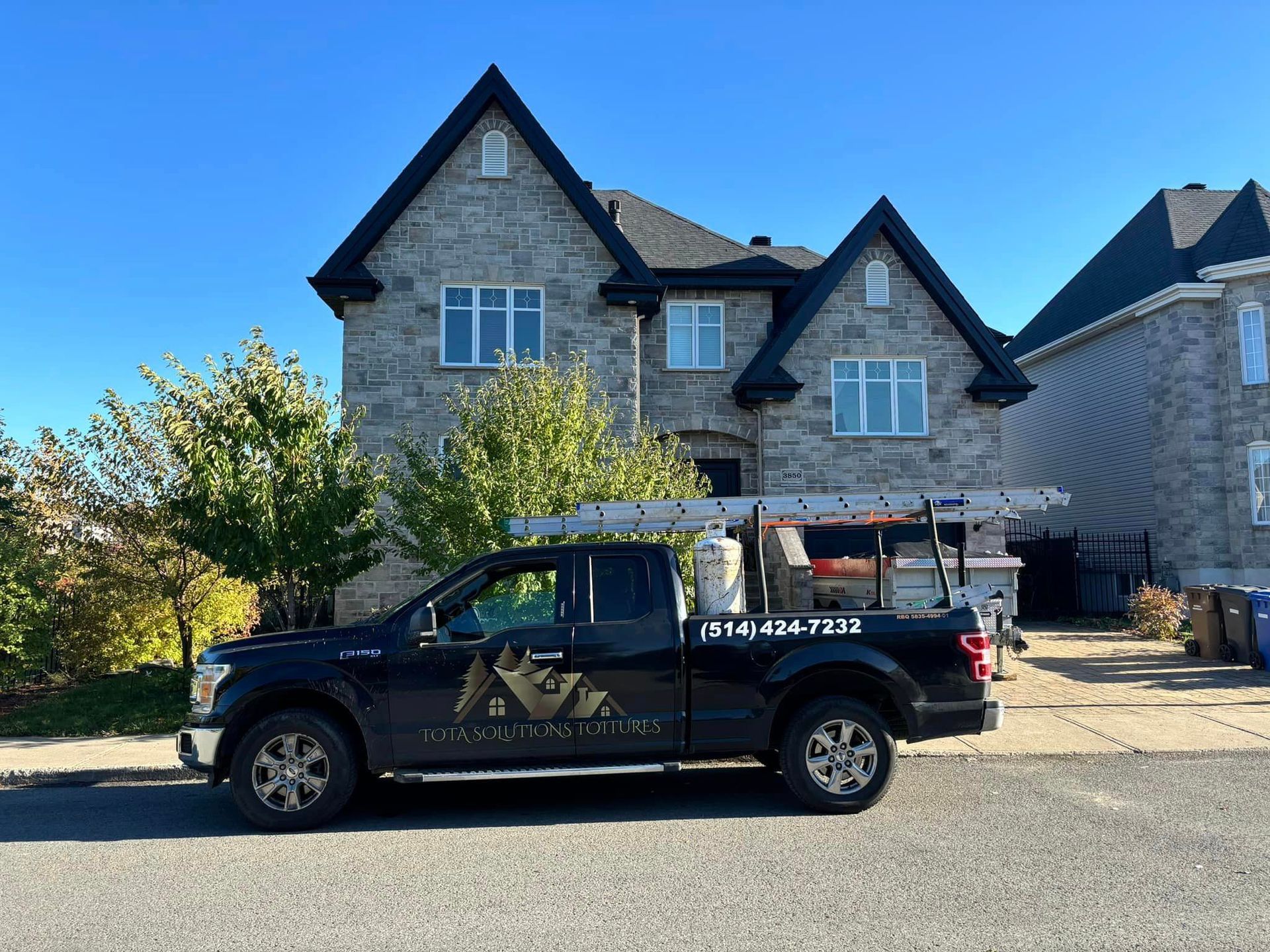 Un camion noir est garé devant une grande maison.