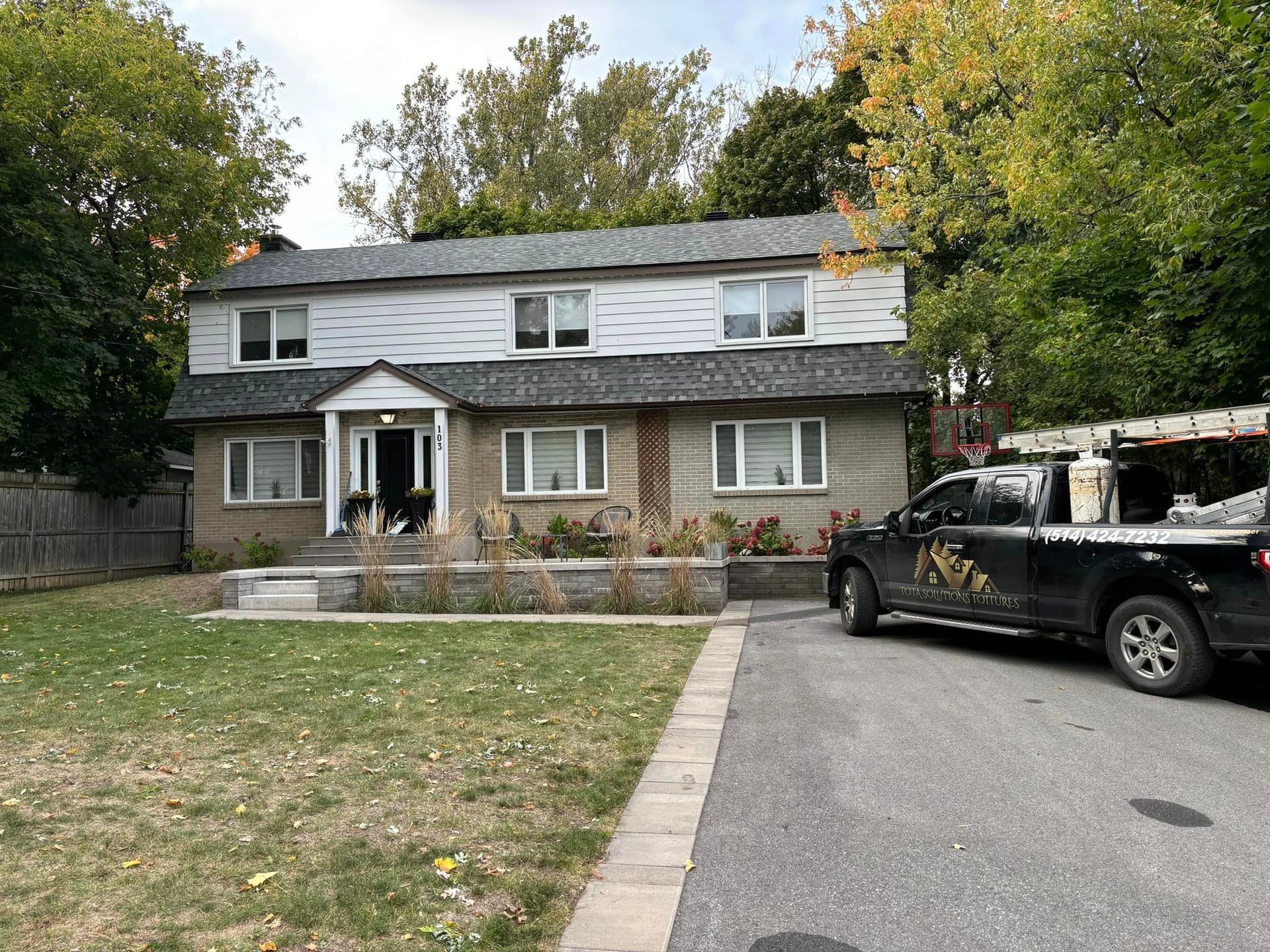 Un camion noir est garé devant une maison.