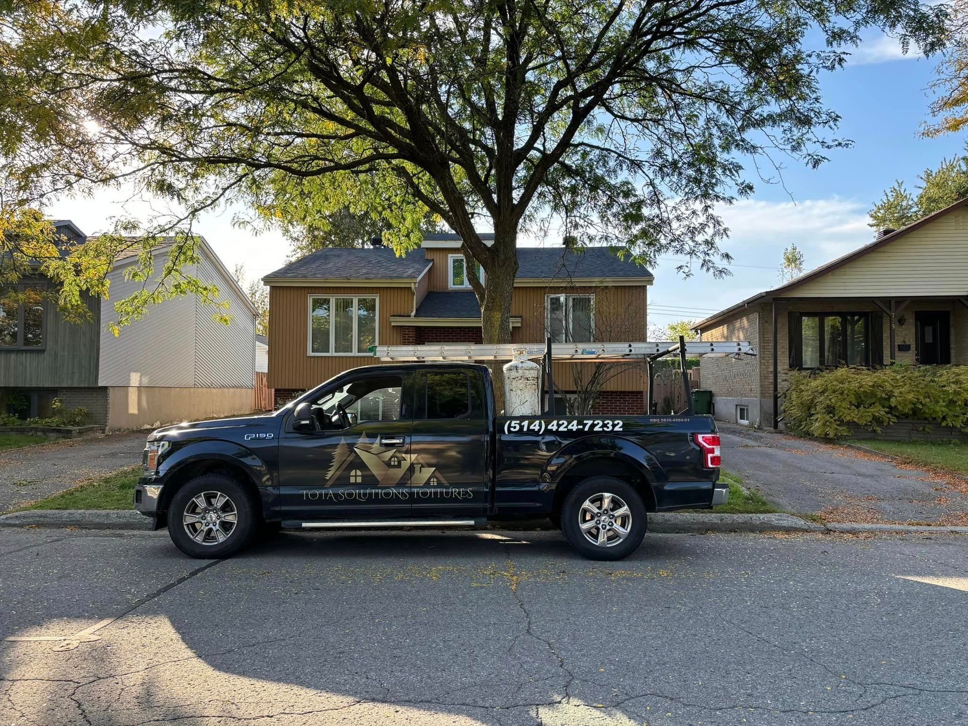 Un camion noir est garé devant une maison.