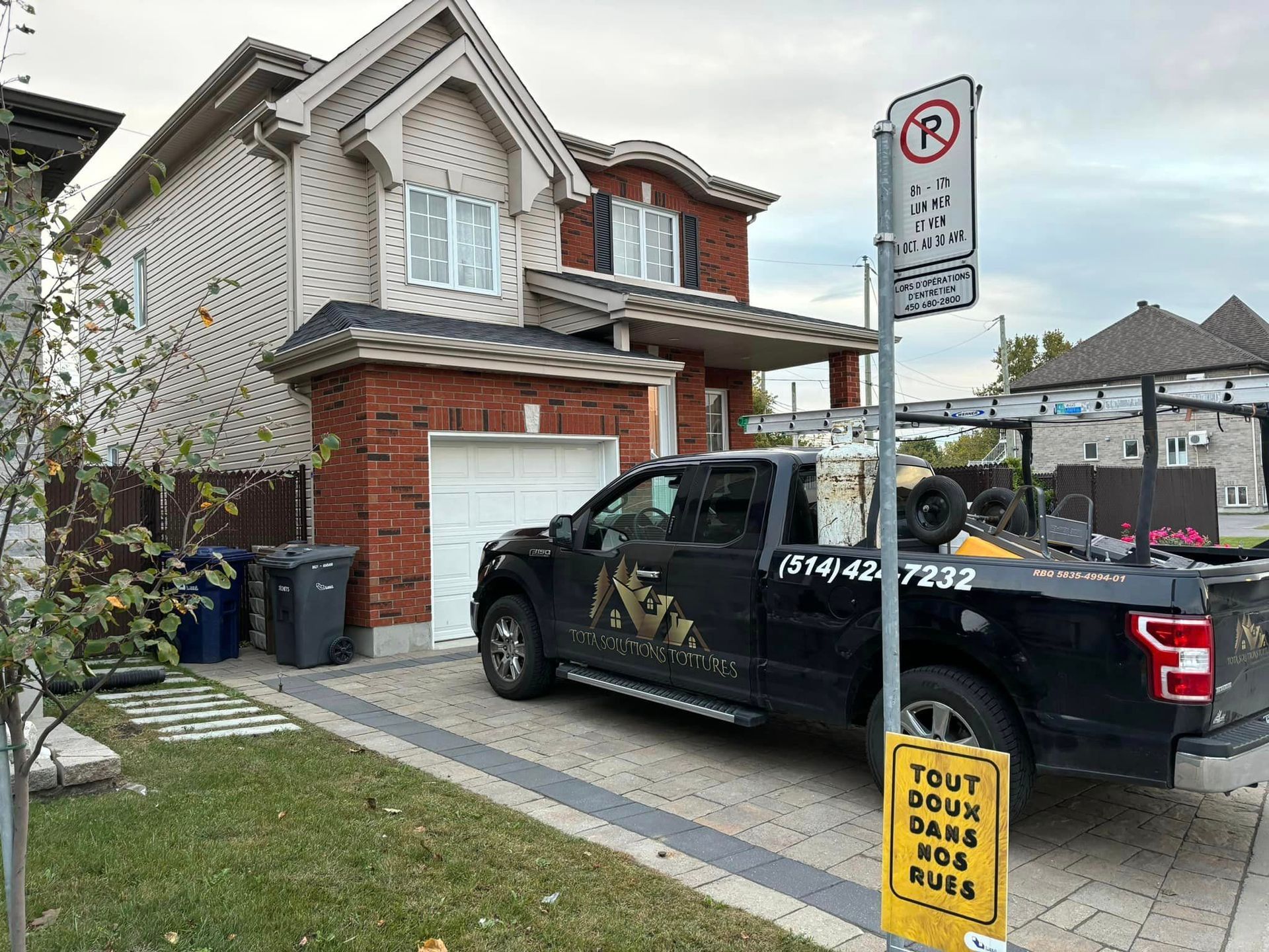Un camion noir est garé devant une maison.