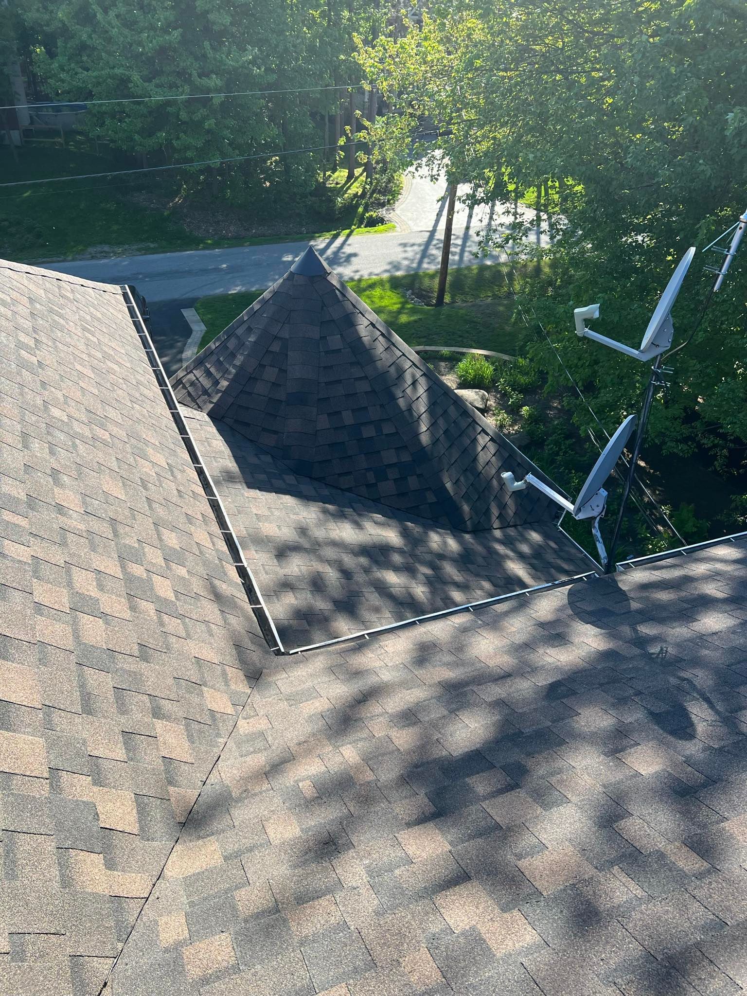 Un toit avec un toit en forme de pyramide et des arbres en arrière-plan.