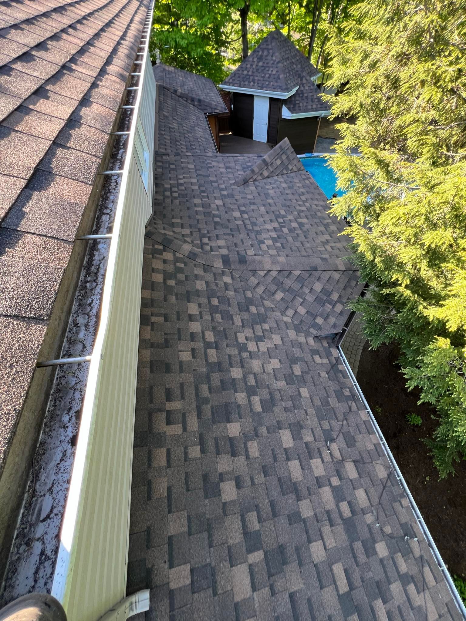 Un toit avec une gouttière dessus et une piscine en arrière-plan.