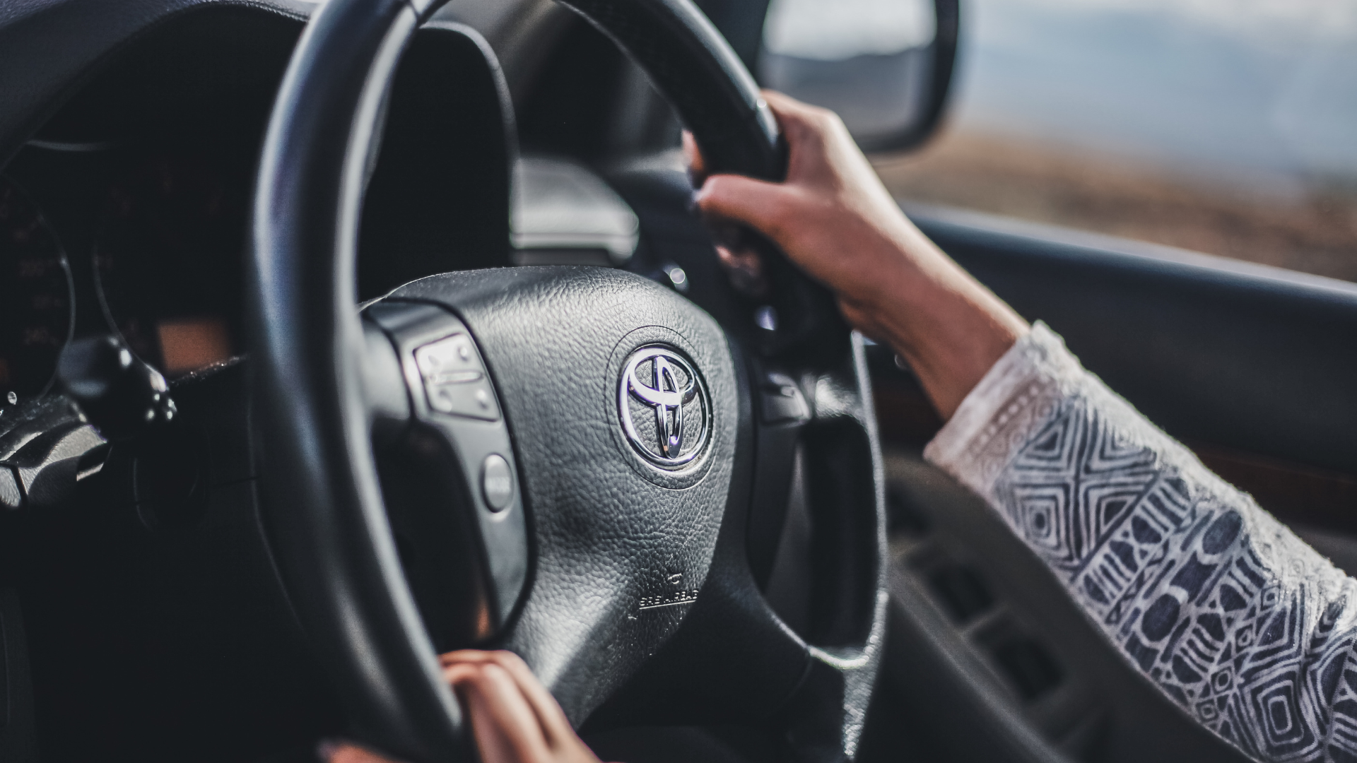 A person is holding the steering wheel of a car.