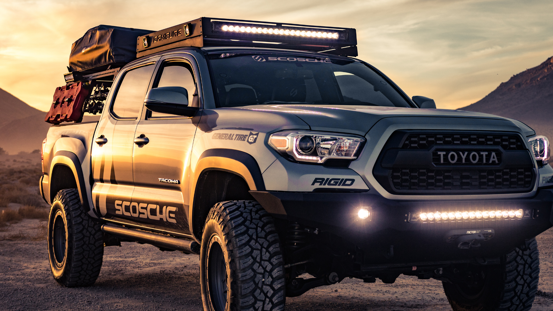 A toyota tacoma truck with a roof rack on top of it is parked in the desert.