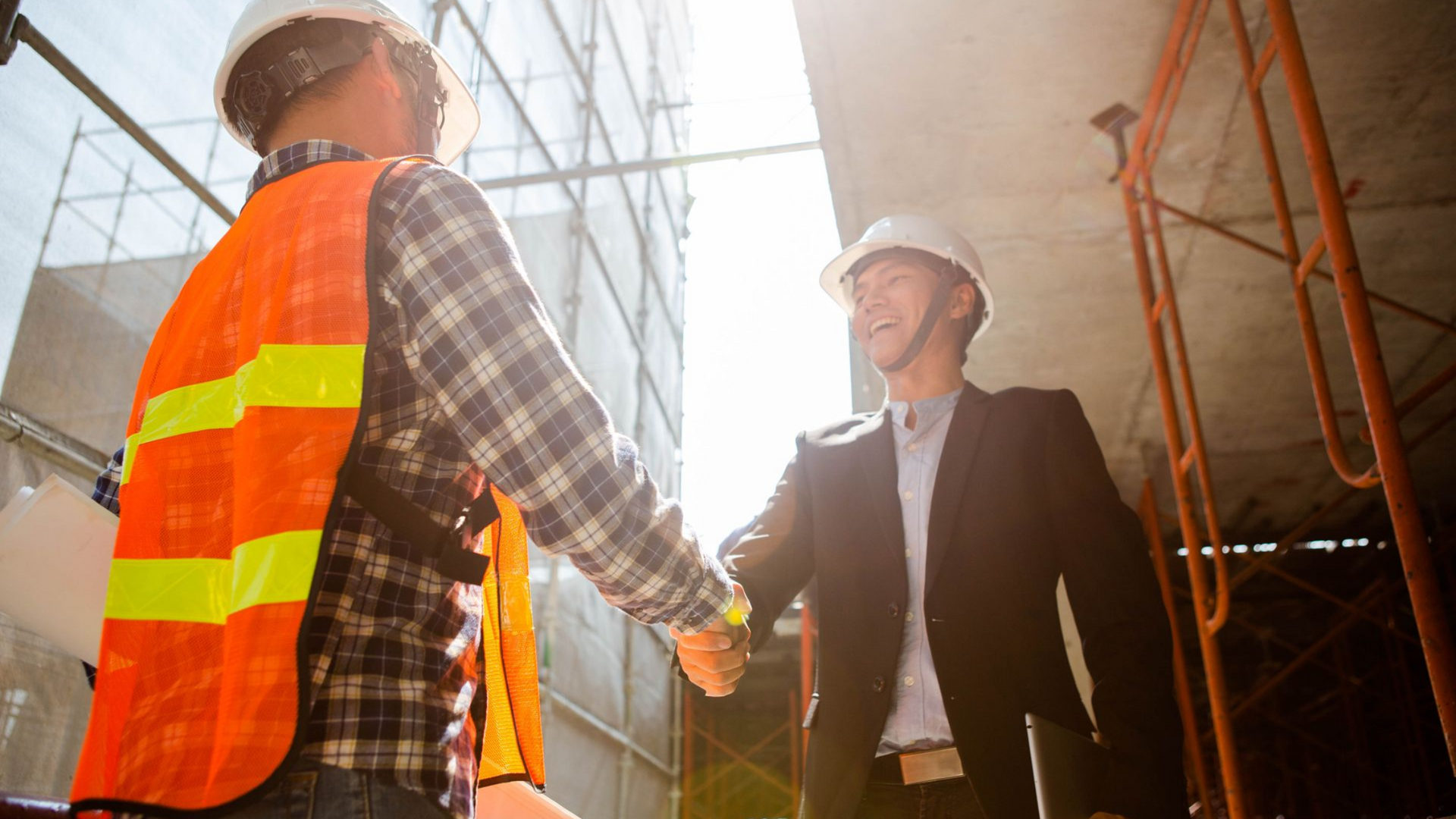 Construction worker and investor shaking hands.
