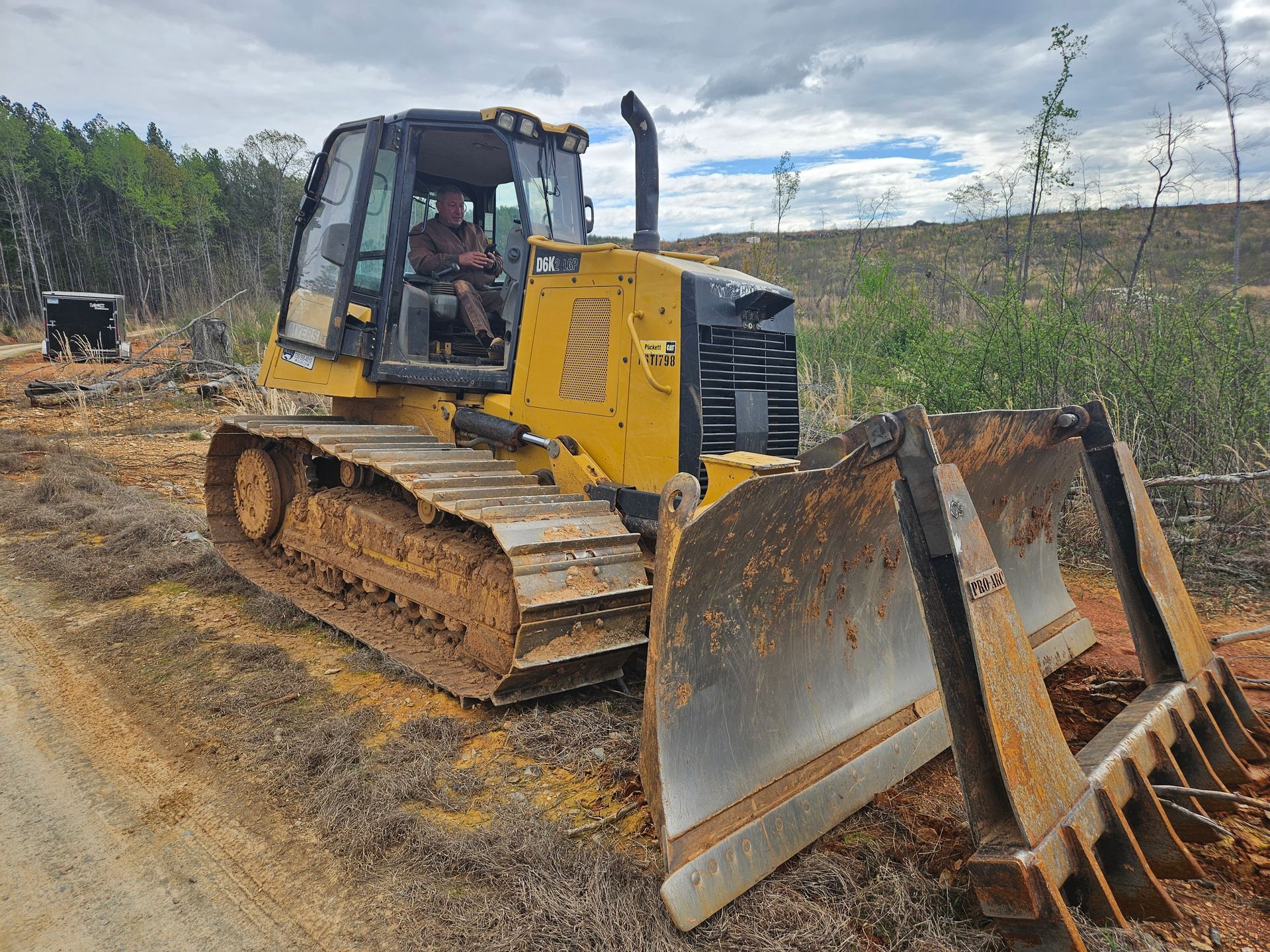 A bulldozer is sitting on the side of a dirt road.