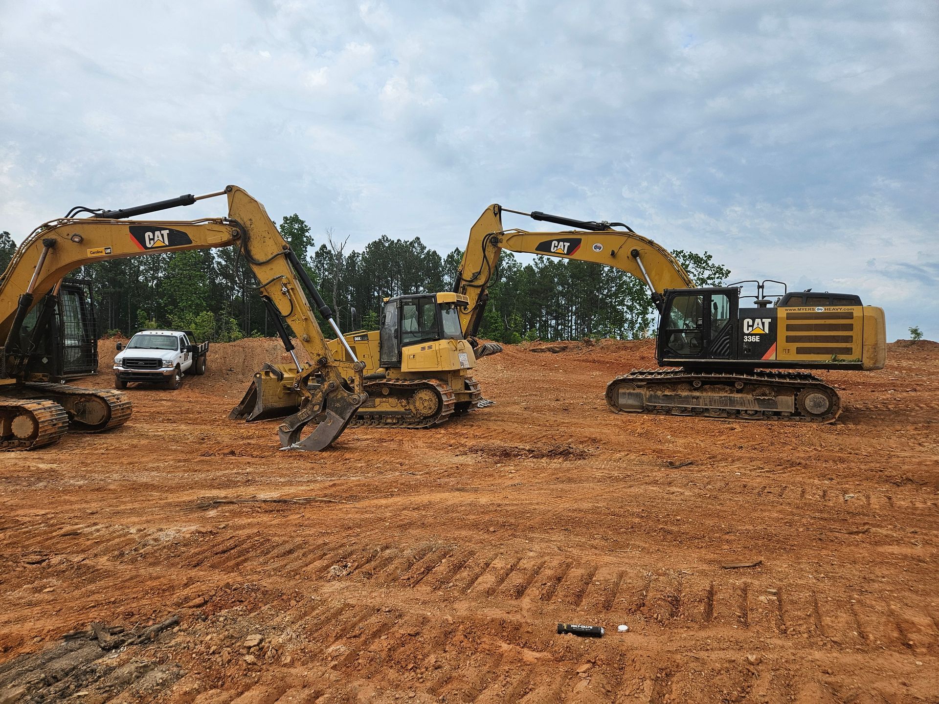 Two excavators are parked in a dirt field.