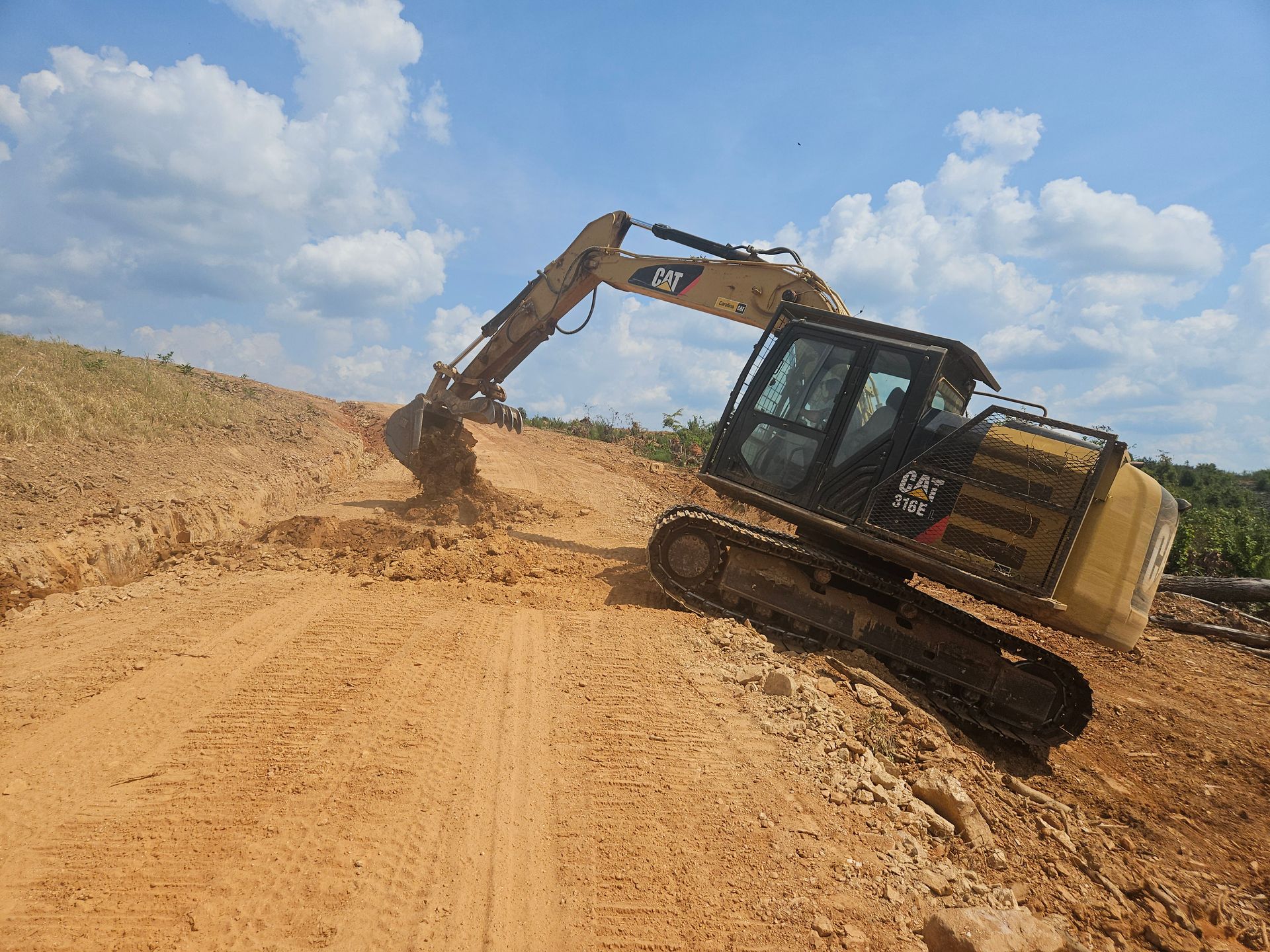 A large excavator is moving dirt on a dirt road.