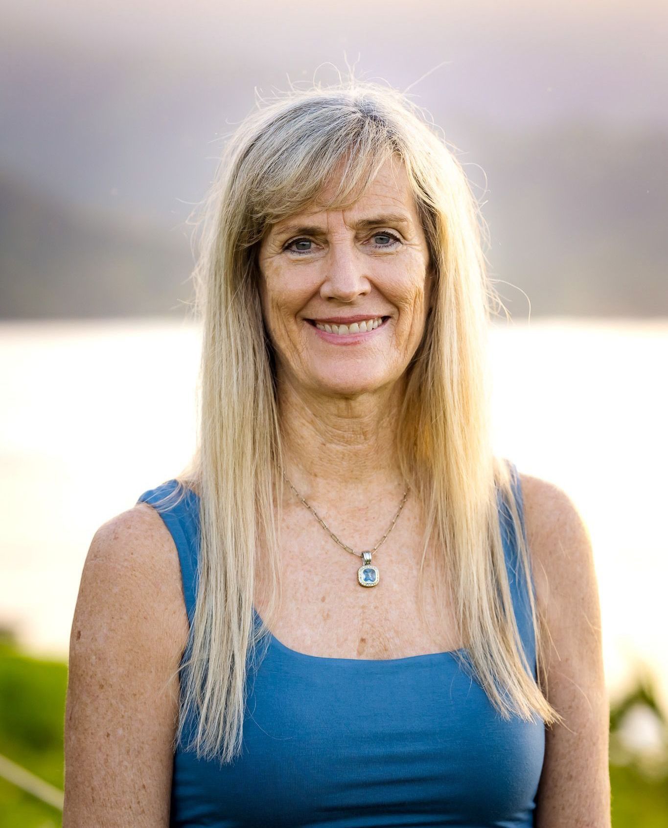 A woman is sitting at a desk with a laptop and a vase of flowers.