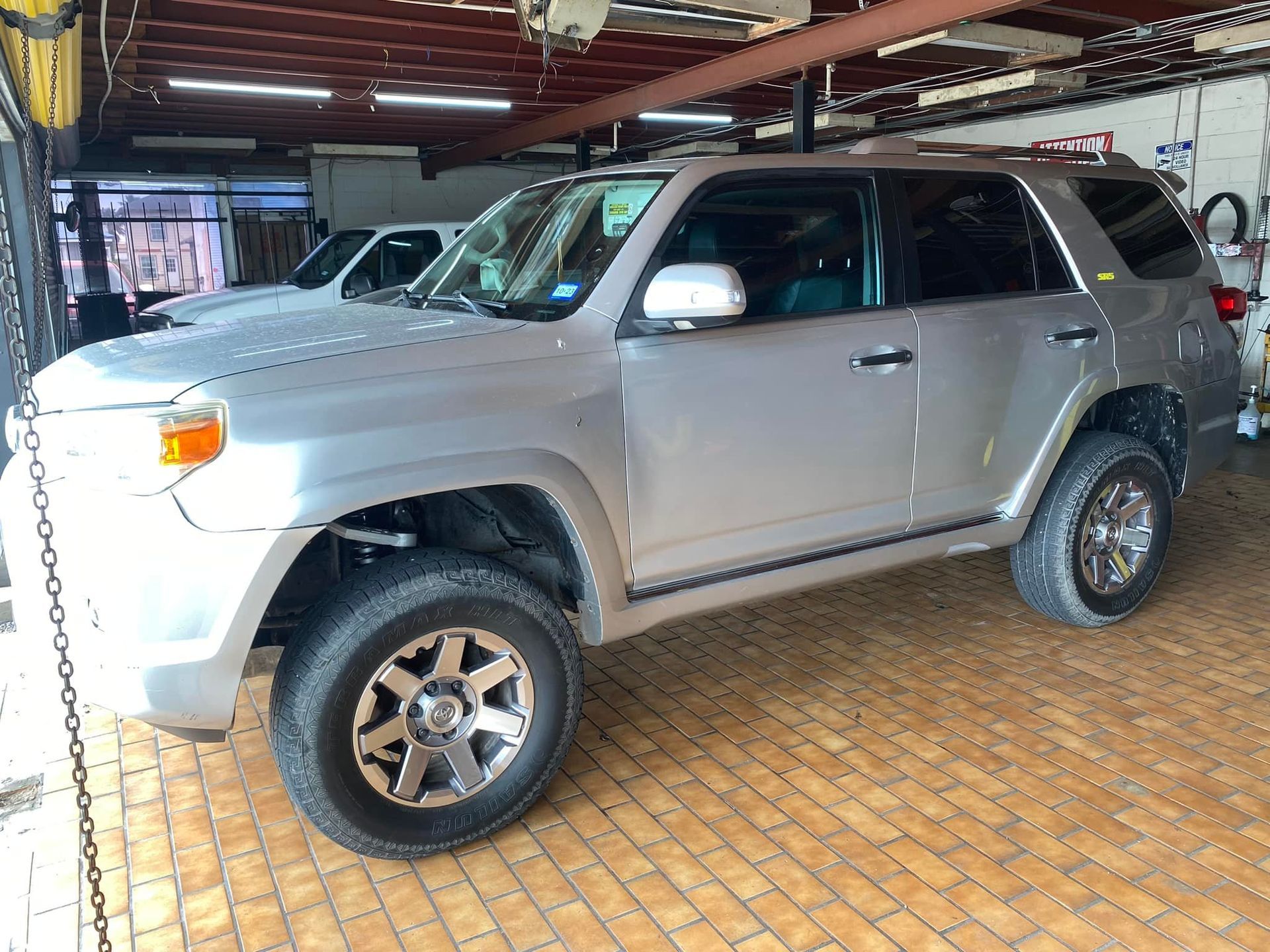 Silver Toyota 4Runner parked inside a garage, with tinted windows and off-road tires.