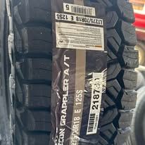 Close-up of a black Nitto Grappler A/T tire with size and specification labels.