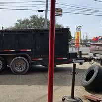Dump truck, red pole in foreground, parked near a tire. Bright day, outdoors.