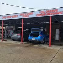 Blue car parked under an auto shop awning; sign reads 