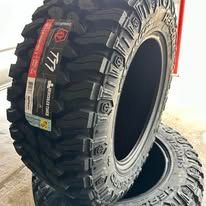 Two black off-road tires, one with a red and white label, stacked on each other.