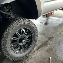 Close-up of a black truck wheel and tire on a concrete surface.