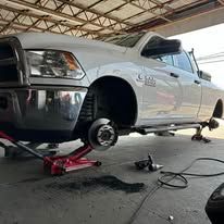 White pickup truck being worked on in a repair shop, tire removed.