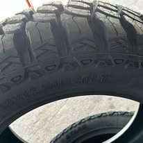 Close-up of a black mud terrain tire with deep treads and sidewall lettering.