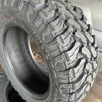 Close-up of a large, black mud terrain tire with deep tread.