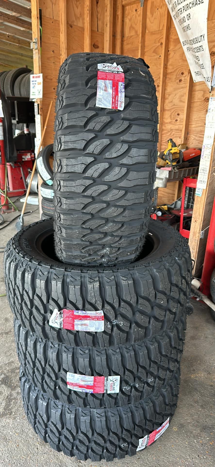 Four stacked black tires with deep treads, indoors.