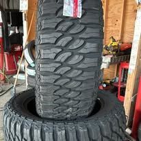 Two large black off-road tires stacked on top of each other, displayed indoors.