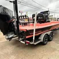 Orange and black boat on a trailer, outside.