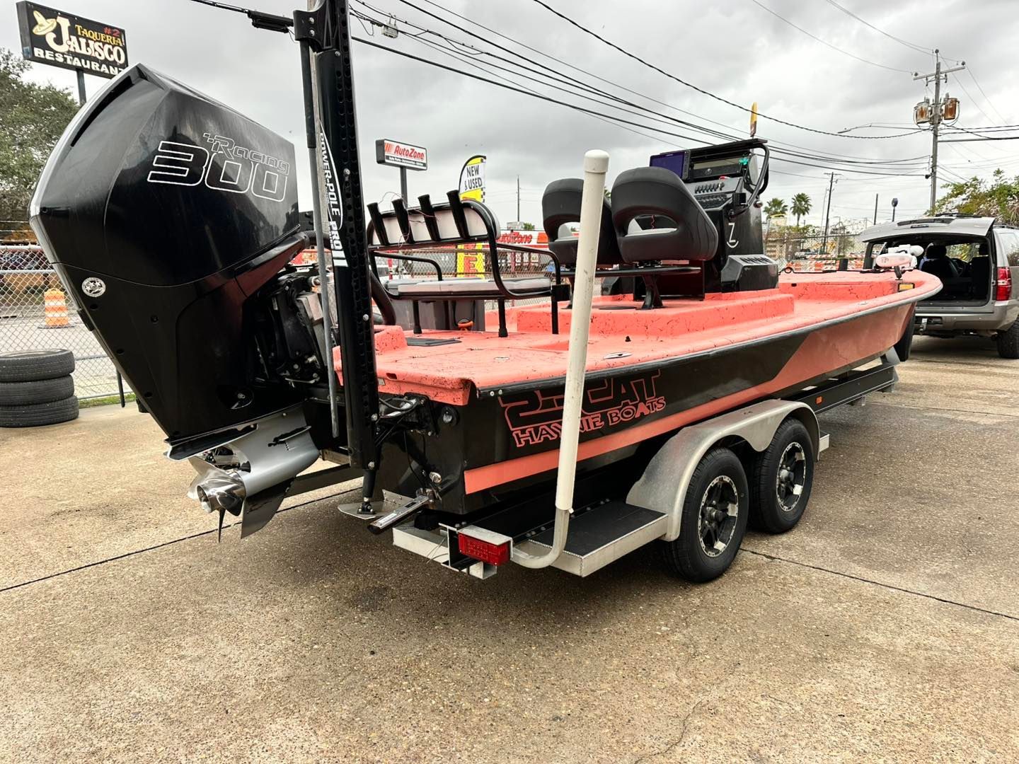 Orange and black fishing boat on a trailer, with a large motor.