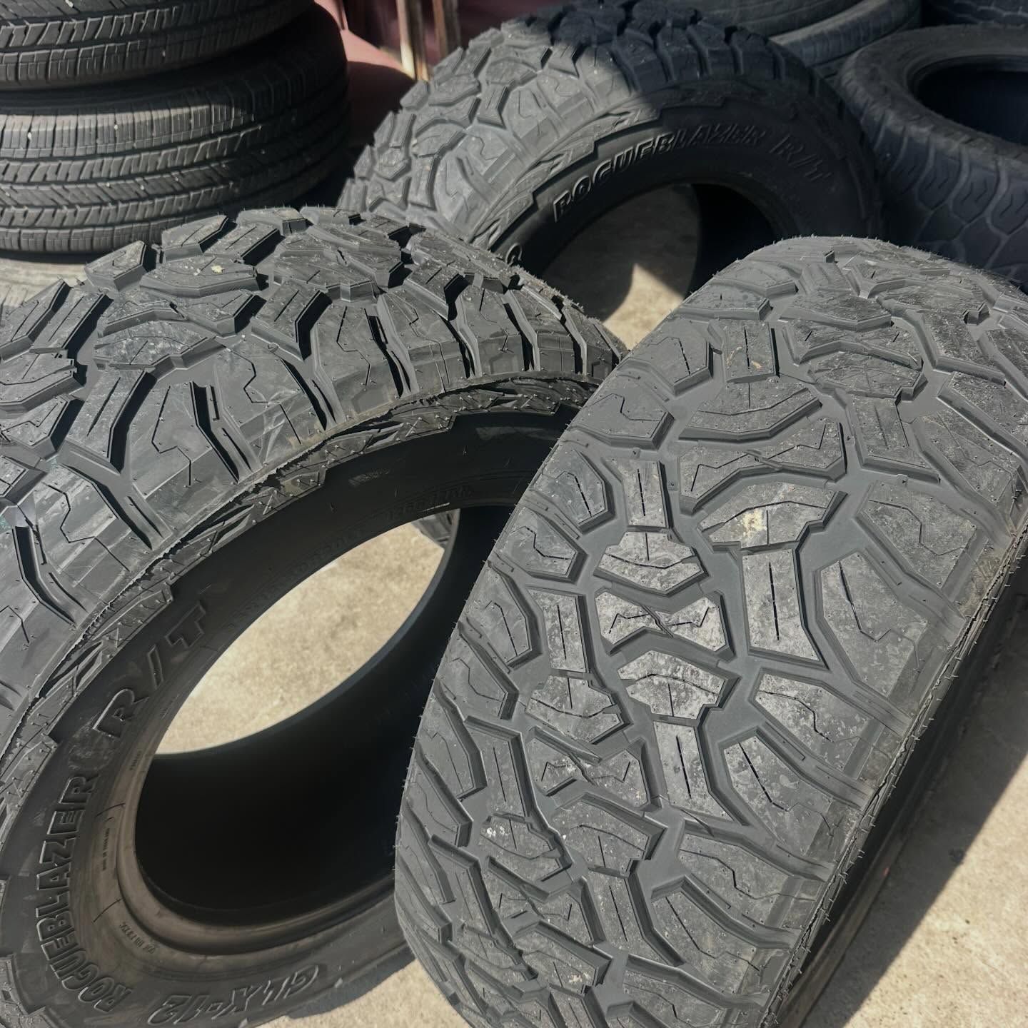 Several worn, dark-treaded tires piled up outdoors, likely for sale or disposal.