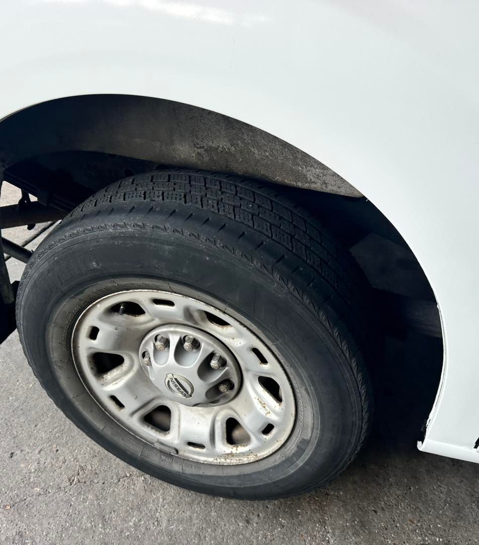 White vehicle's tire and wheel. Gray tire, silver rim, and white body panel are visible.