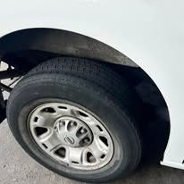 Close-up of a white vehicle's wheel and tire; the tire is black and the rim is silver.