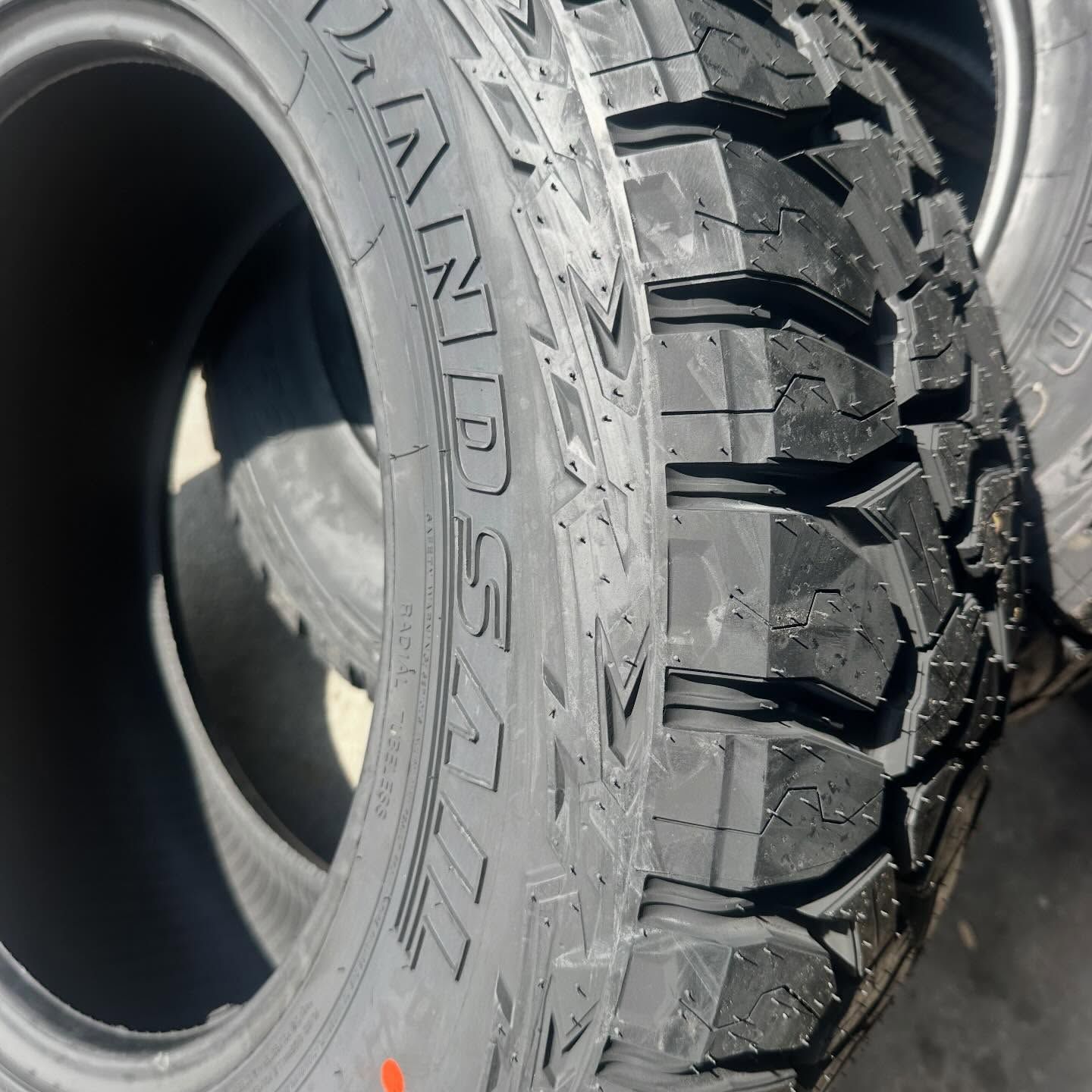 Close-up of a new tire with deep treads and the brand name 