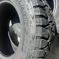 Close-up of two off-road tires with deep treads, one in front of the other.