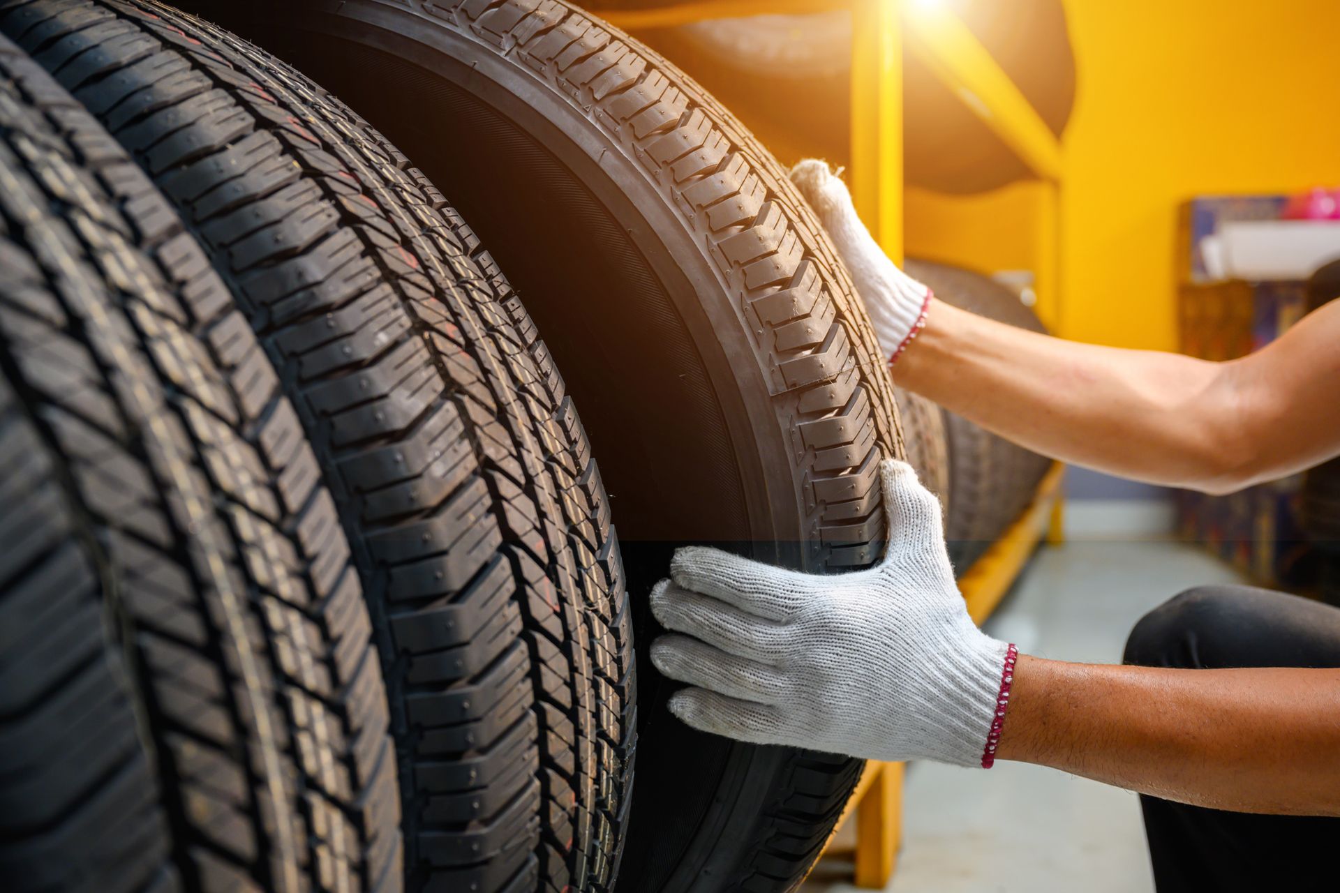 Person in gloves holding a tire in a storage area. Person in gloves holding a tire in a storage area.