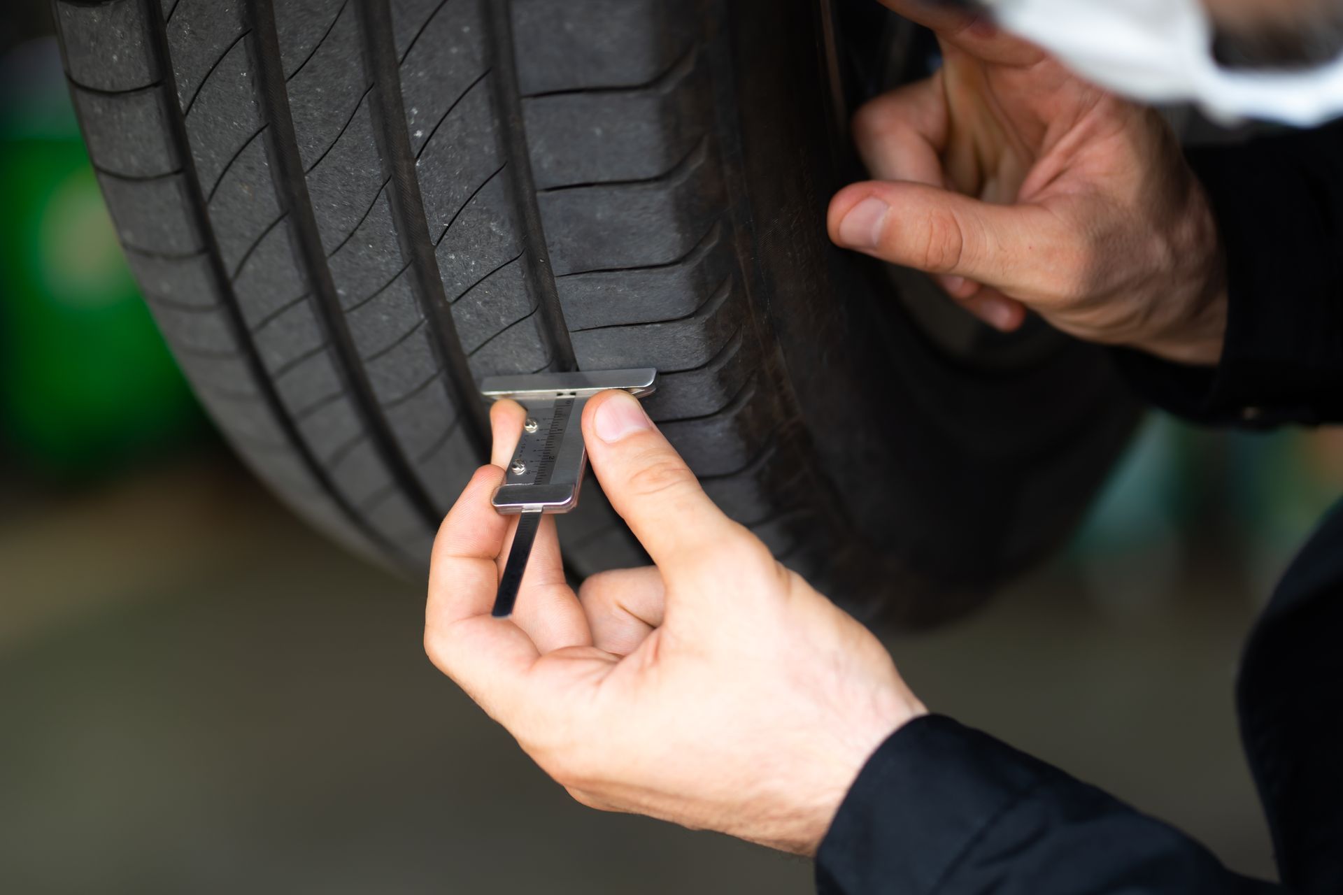 Person using a tire tread depth gauge to measure tire wear.